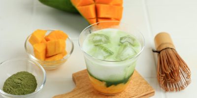 Close Up Homemade Iced Mango Matcha Latte on White Table